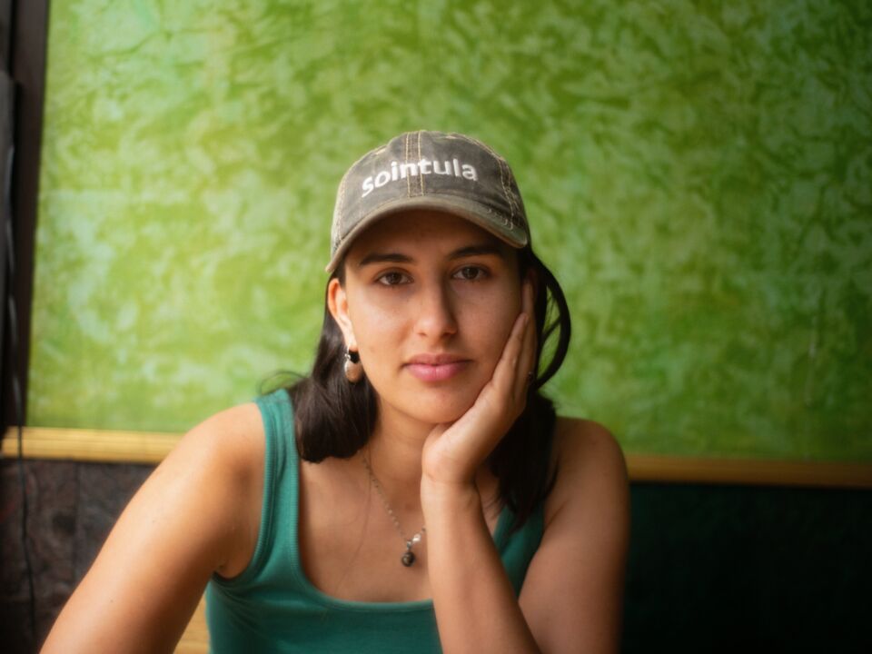 Author Audrey Popa poses in front of green wallpaper.
