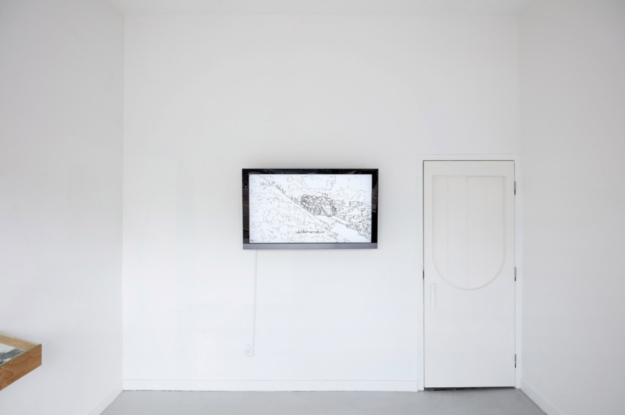 A framed drawing is hung in the middle of a white-walled room.